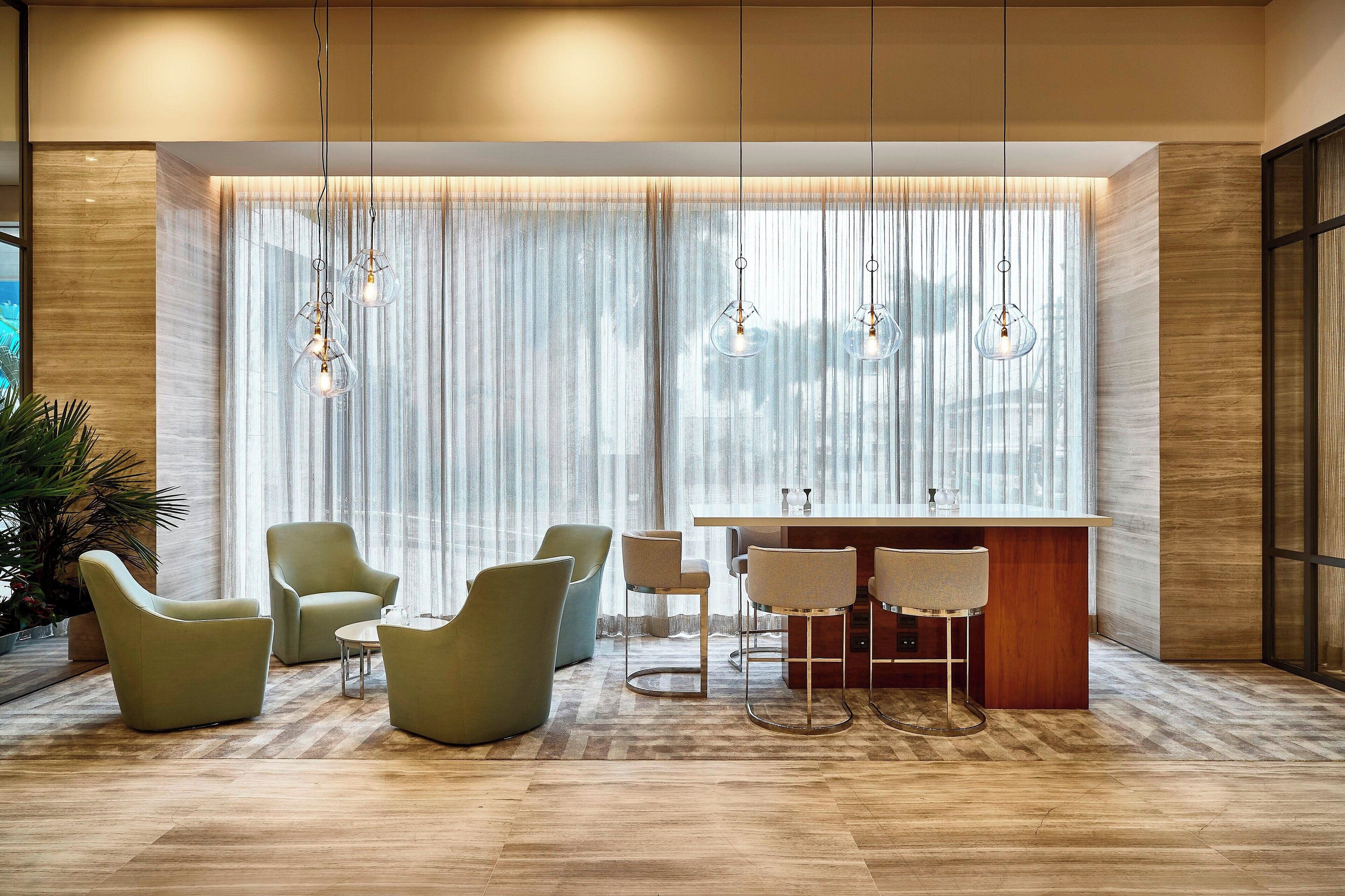 Un interior moderno con zona de bar, asientos y ventanas amplias con cortinas translúcidas.