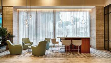 Un interior moderno con zona de bar, asientos y ventanas amplias con cortinas translúcidas.