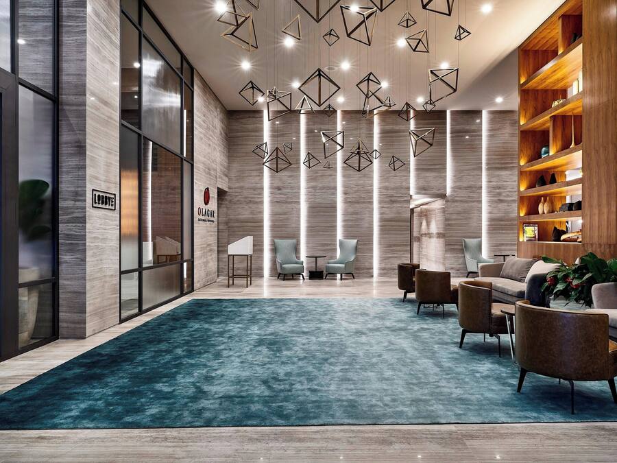 Un vestíbulo moderno con alfombra color turquesa, estanterías de madera y muebles contemporáneos.