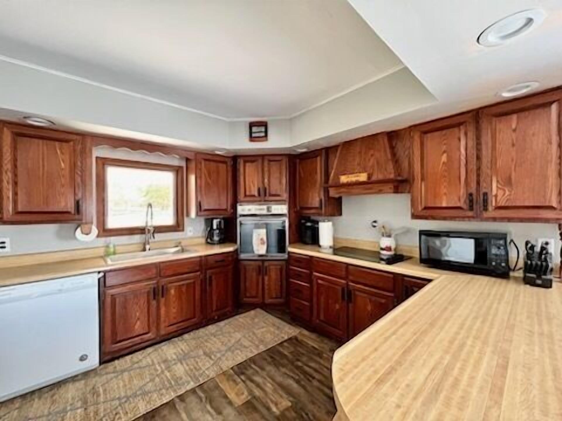 A compact kitchen with wooden cabinets, a built-in oven, a microwave, and a small sink.