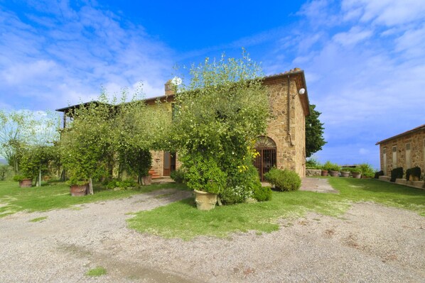 An old stone building with a gravel driveway and potted plants.