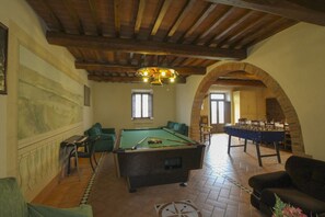 A room with a pool table, a foosball table, and a sofa.