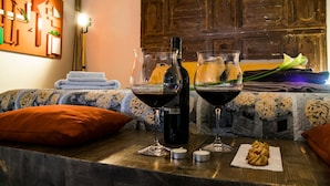 Une pièce chaleureuse avec une table en bois, mise avec deux verres à vin, une bouteille et une pâtisserie.
