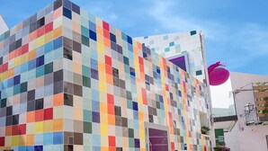 Un bâtiment doté d’une façade ornée d’une mosaïque colorée, d’une sculpture en forme de ballon rose bien visible et d’une enseigne indiquant un parc culturel à thème agricole.