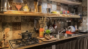 Une cuisine équipée d’une cuisinière à gaz, de casseroles suspendues, d’un évier et de divers ustensiles de cuisine.