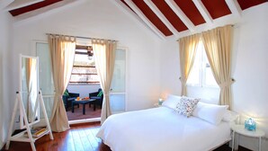 A bedroom with a large bed, a small bedside table, and a window with curtains.