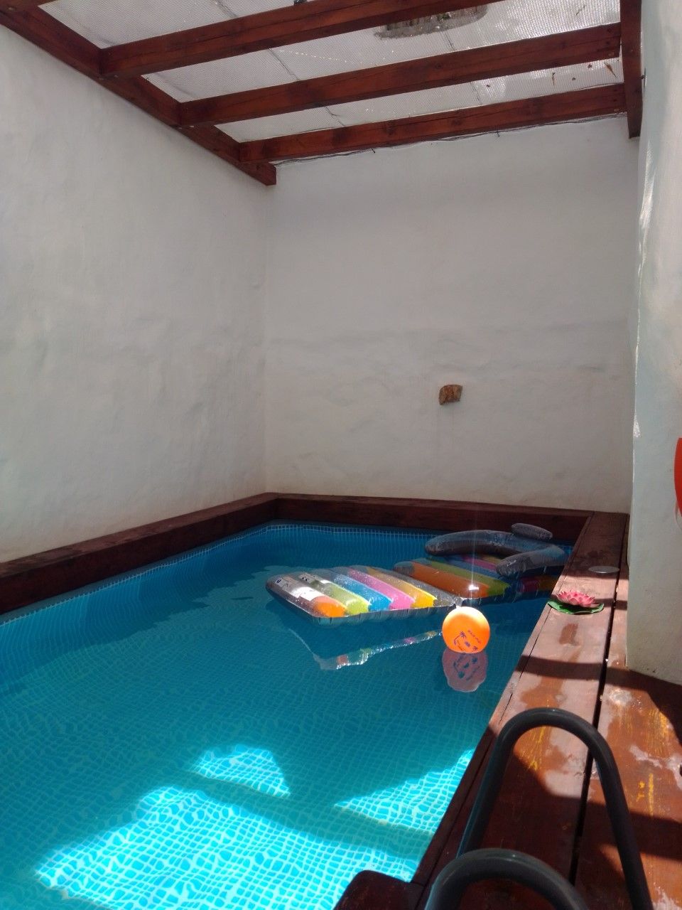 A small indoor pool with a wooden deck and a ladder.