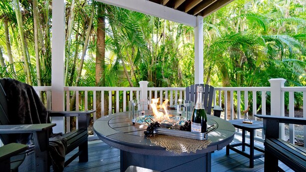 Une terrasse extérieure avec une table ronde, des chaises et un foyer.