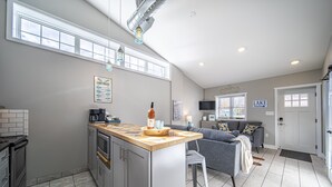 Une cuisine moderne dotée d’un îlot central, de meubles de couleur grise et d’une grande fenêtre.