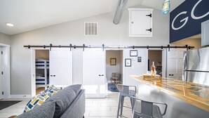 Une cuisine moderne dotée d’un réfrigérateur en acier inoxydable, d’un coin bar et d’un placard avec une porte coulissante de style rustique.