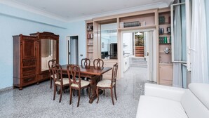 Une pièce spacieuse comprenant une table à manger et des chaises, une grande armoire en bois et un canapé blanc.