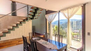 A dining area with a table and chairs, a staircase, and a view of the outdoors. - Stunning modern villa - just half hour to Barcelona! (Caldes De Montbui)