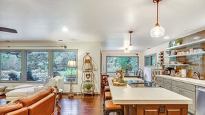 A spacious living area with a large window, a sofa, and a dining table. - Fishing & Rafting: McKenzie River Cabin! (Mckenzie Bridge)