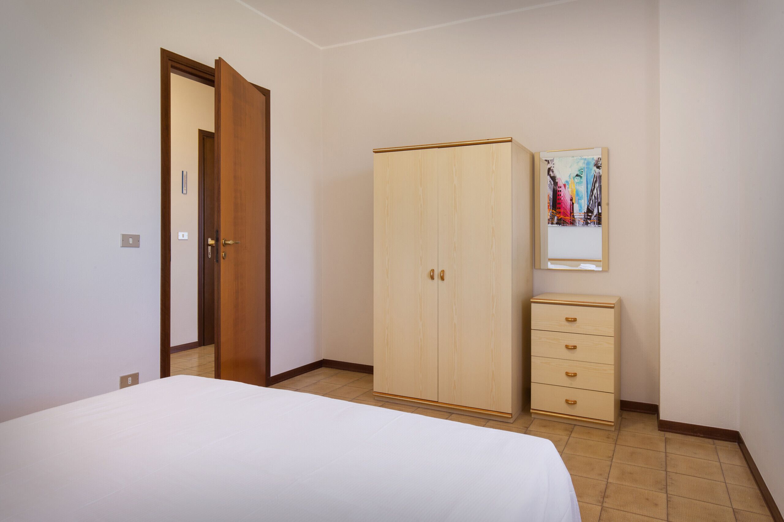 Ein Schlafzimmer mit Bett, Kleiderschrank, Schminktisch und einem Bild an der Wand.
