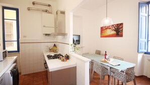 A compact kitchen with a dining area, a built-in stove, and a dining table with chairs. - Walk to the Colosseum from your Family Apt (Roma)