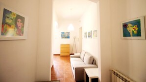 A hallway with a sofa, a small table, and artwork on the walls. - Walk to the Colosseum from your Family Apt (Roma)