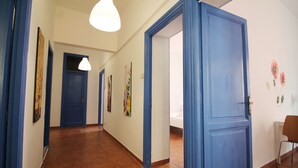 A hallway with blue doors, a white ceiling light, and a chair in the corner. - Walk to the Colosseum from your Family Apt (Roma)
