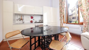 Una cucina compatta con mobili bianchi, un tavolo rotondo e sedie in vimini.