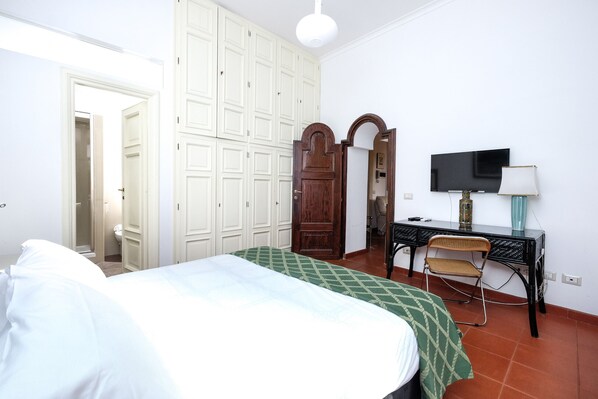 Une chambre à coucher comprenant un lit, un bureau, une chaise, une télévision et une armoire.