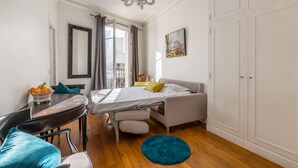 A bedroom with a bed, a desk, a chair, a dresser, and a window with curtains.