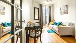 A living room with a sofa, dining table, chairs, and a chandelier.