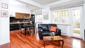 A spacious living room with a black leather sofa, a wooden coffee table, and a dining area with a black table and chairs. - Enjoy the Sunset on Your Vatican Terrace (Roma)
