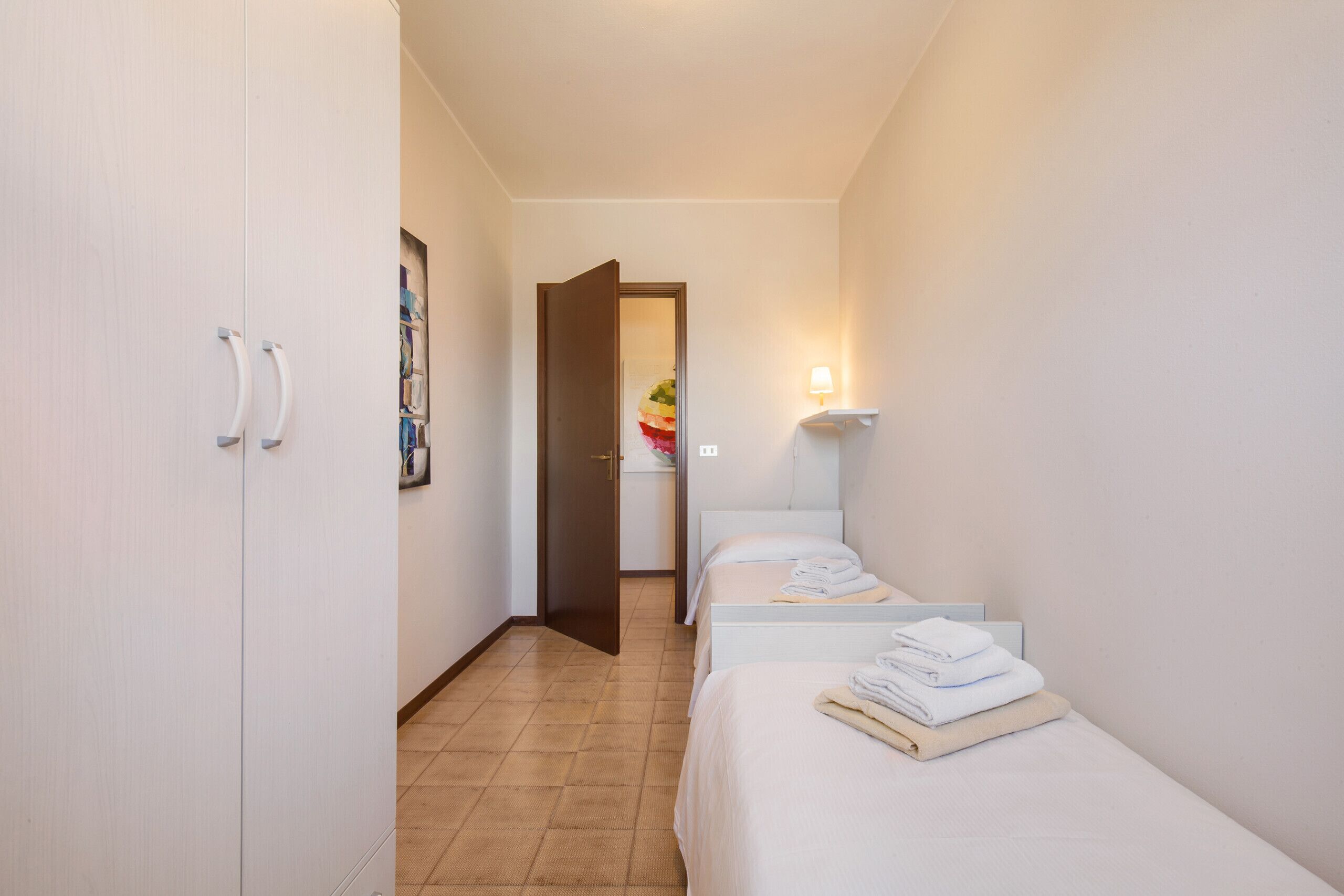 A hotel room with a bed, a bedside table, a lamp, and a wardrobe.