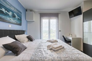 Relax in comfort with a neatly made bed and a spacious workspace near a large window.