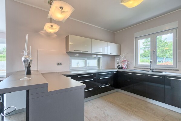 A modern kitchen with black and white cabinetry, a central island, and pendant lighting.