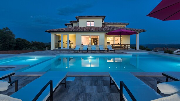 A modern house with a swimming pool, lounge chairs, and a patio area.