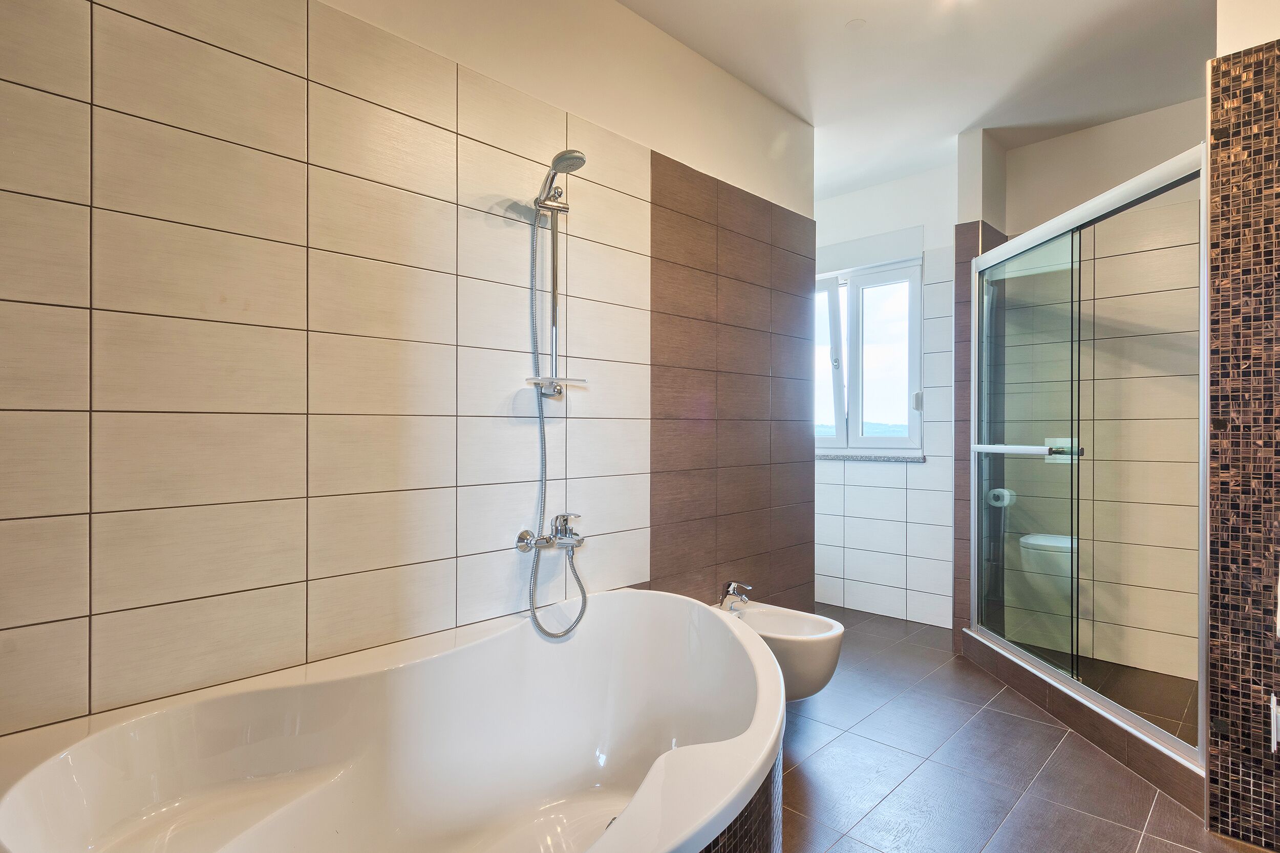 A modern bathroom with a freestanding bathtub, a glass shower enclosure, and a toilet.