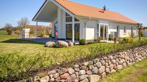 A modern house with a sloped roof, large windows, and a stone retaining wall. - located at the sea, stunning view over Hiddensee and the iconic lighthouse (Trent OT Vaschvitz)