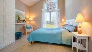 A bedroom with a bed, a chair, a nightstand, and a window with a view. - located at the sea, stunning view over Hiddensee and the iconic lighthouse (Trent OT Vaschvitz)