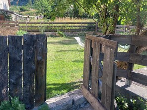 A wooden fence with a stone wall and a grassy area beyond it.