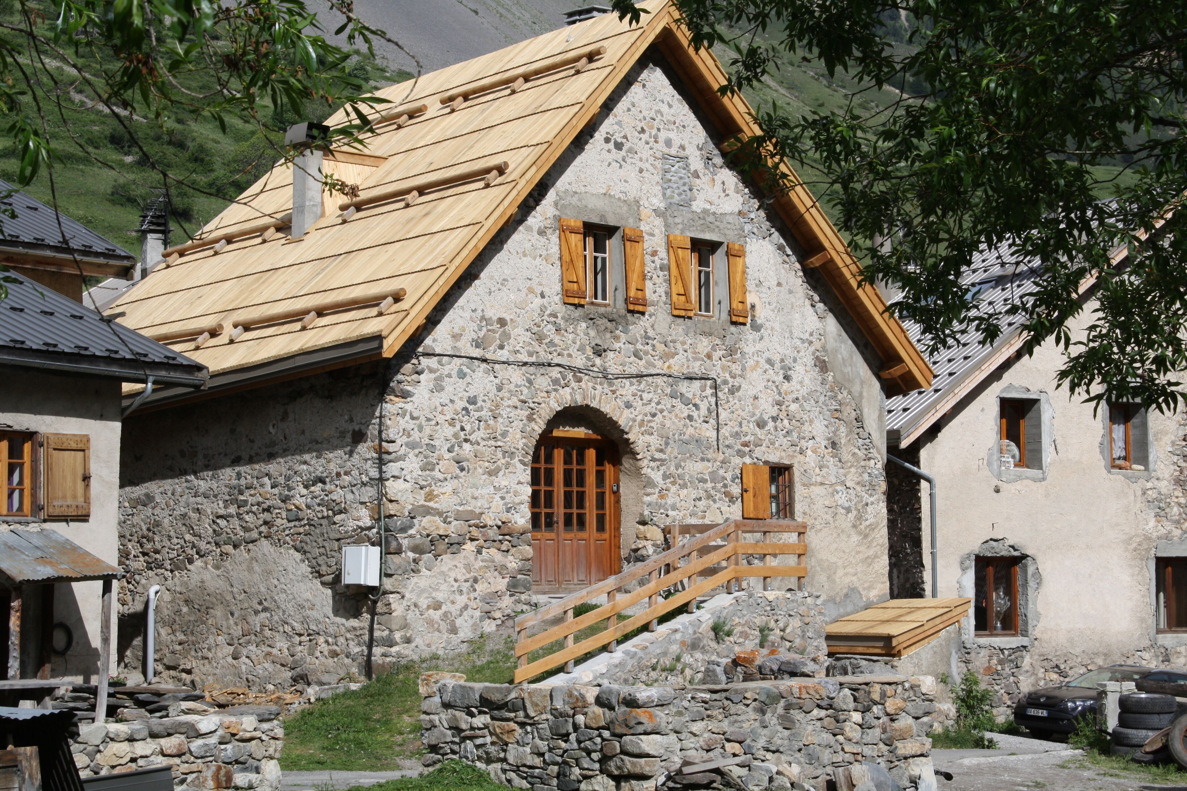 Un bâtiment en pierre avec un escalier en bois menant à une porte en bois.