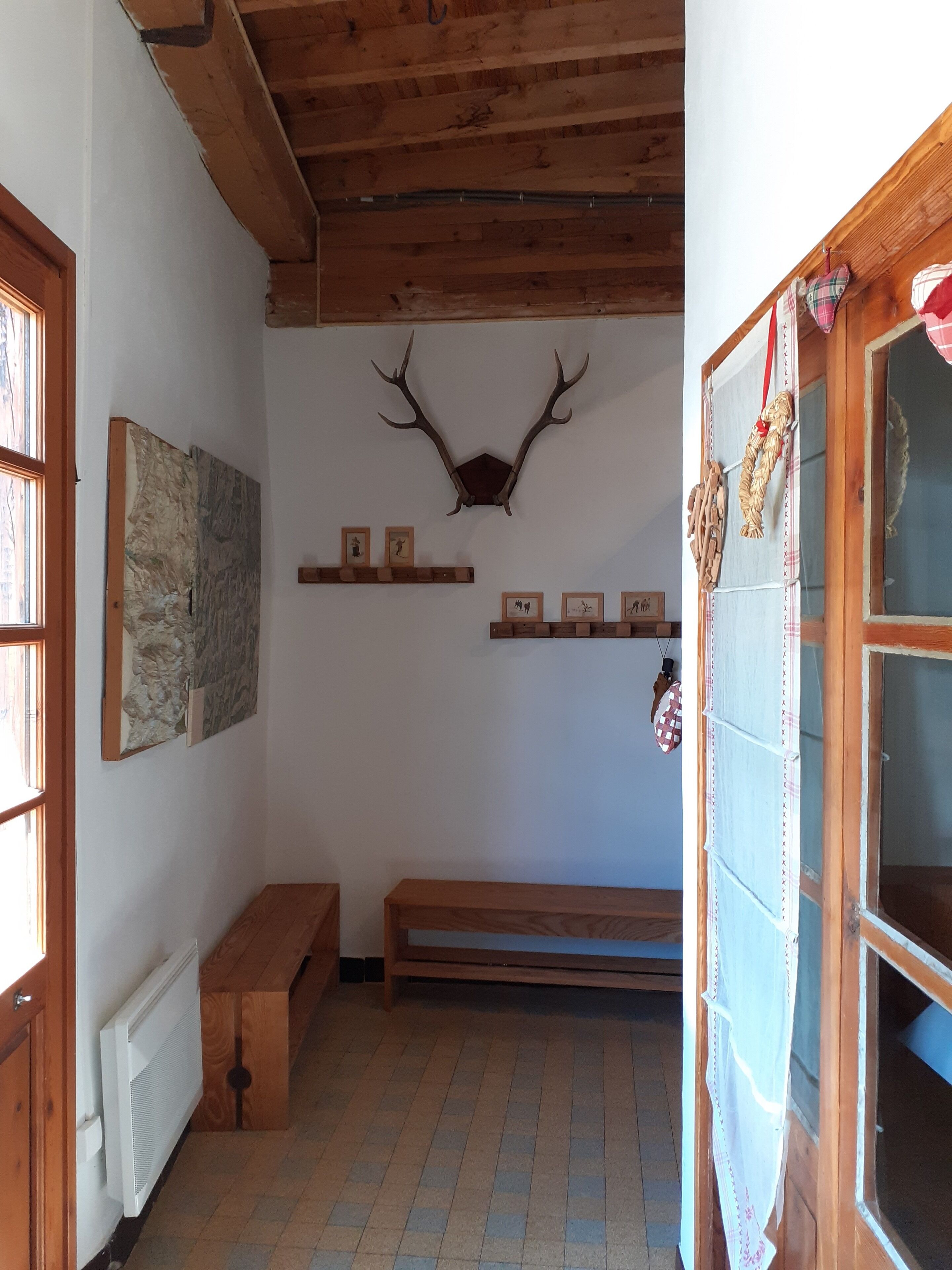 Une pièce avec un plafond en bois, une tête de cerf accrochée au mur et un banc.