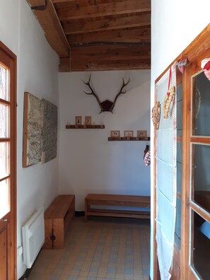 Una stanza con soffitto in legno, una testa di cervo appesa al muro e una panchina.
