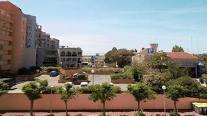 A parking area with multiple cars, surrounded by buildings and trees.