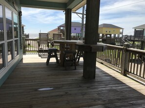 Eine Holzterrasse mit Tisch und Stühlen, mit Blick auf ein Wohngebiet mit Häusern.