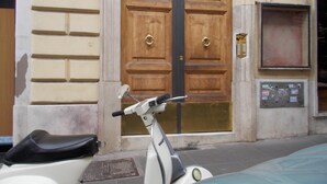 Una patineta estacionada frente a un edificio con una puerta doble de madera y un buzón.