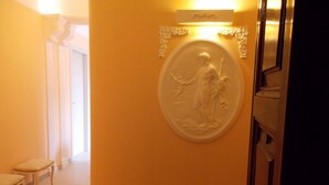 Un pasillo con un relieve circular en la pared, un banco y una puerta.
