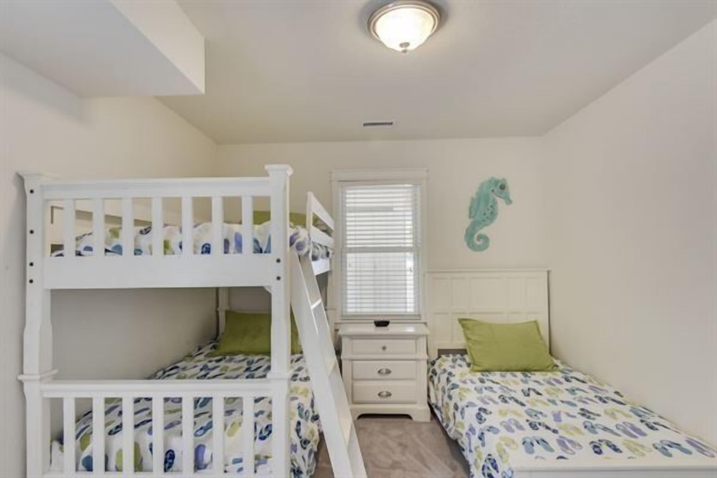 A child's bunk bed with a matching nightstand and a small bed with a seahorse decoration.