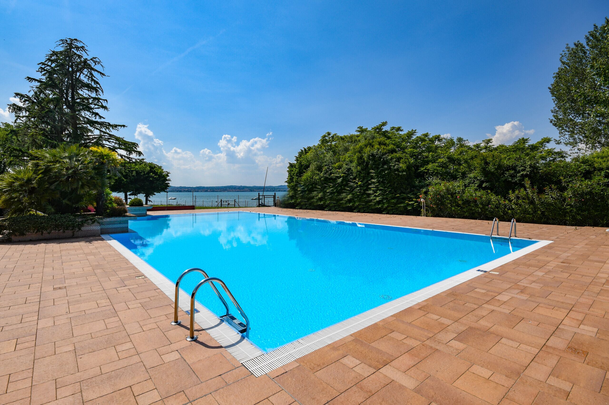 A rectangular swimming pool with a clear blue water surface, surrounded by a brick patio.