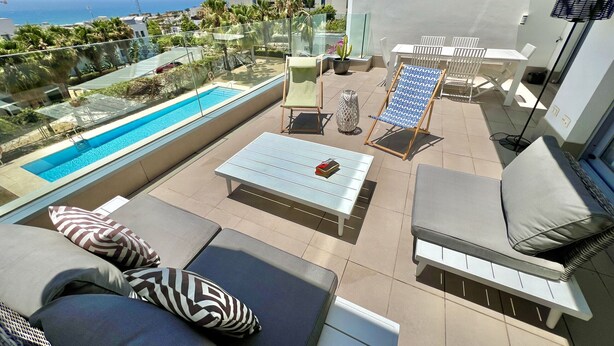 Terraço no telhado com piscina, espreguiçadeiras e uma mesa.