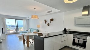 Cozinha moderna com ilha central, área de jantar com vista e grande porta de vidro deslizante para o exterior.