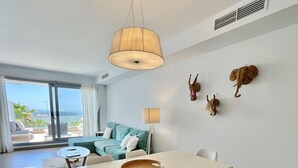Uma sala de jantar moderna com uma mesa branca, cadeiras de madeira e um candeeiro pendente.