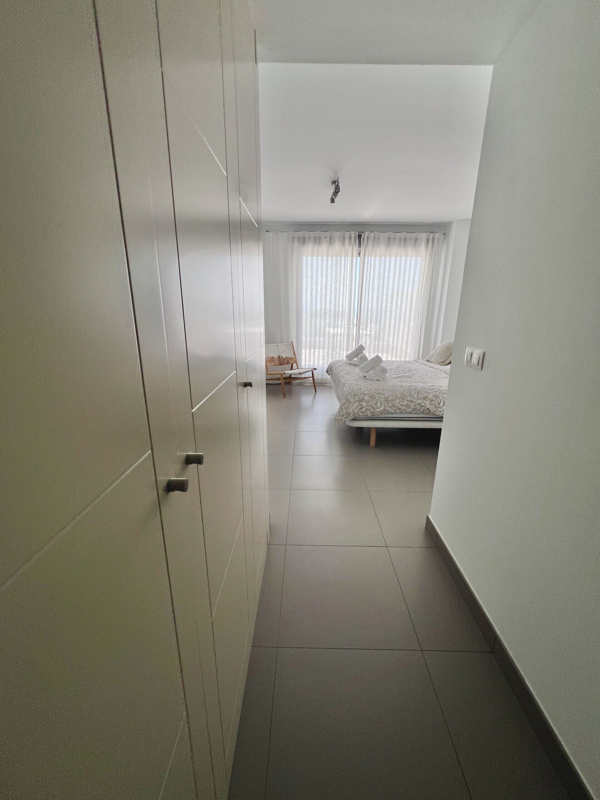 Ein Schlafzimmer mit einem Bett, einem Sessel und einem Fenster mit Vorhängen.