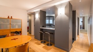 A modern kitchen with a bar area, wooden flooring, and a dining table with chairs. - Pompidou Hideaway, by Veeve (Paris)
