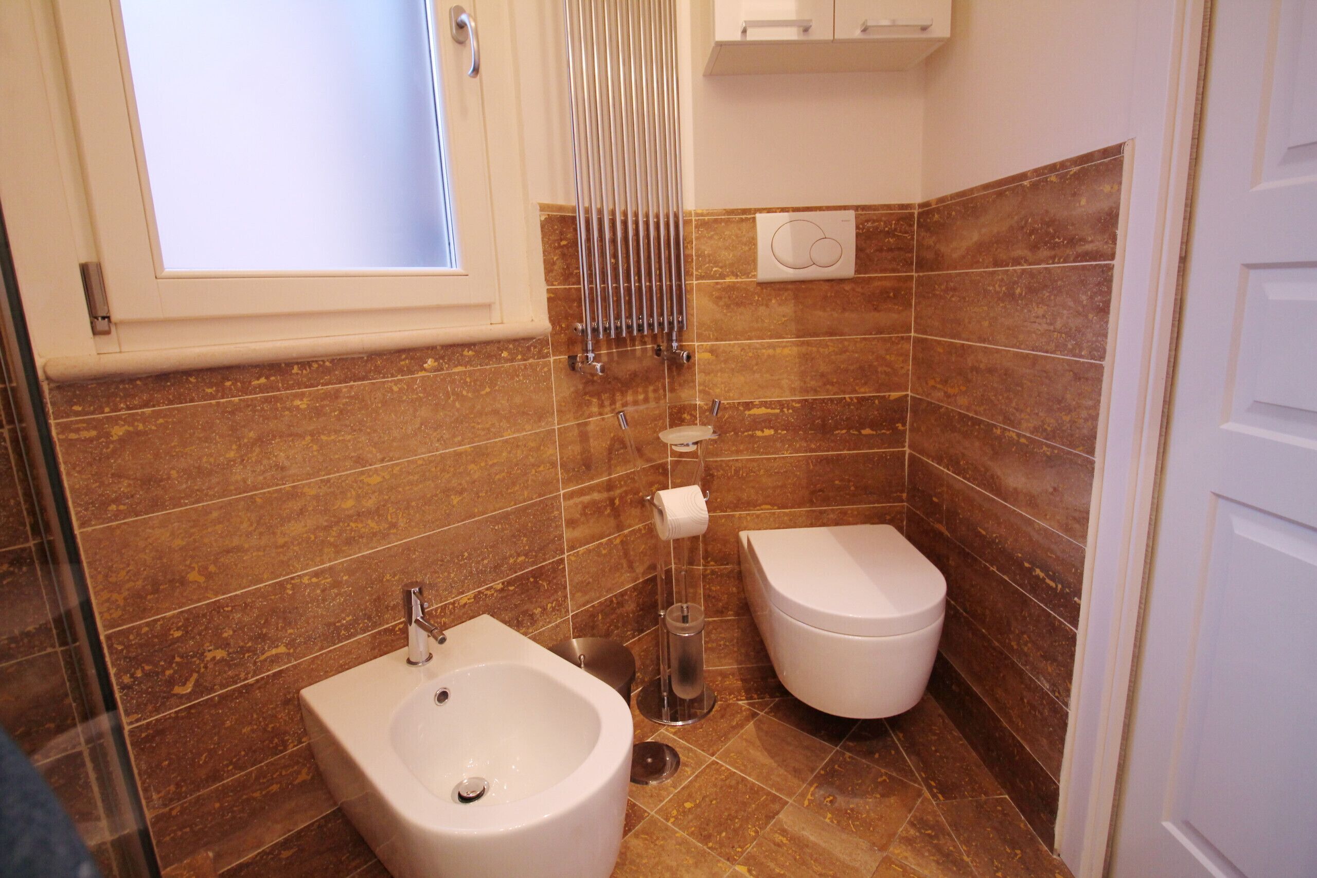 Une salle de bain équipée d’un bidet, de toilettes et d’une fenêtre.