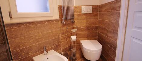 Une salle de bain équipée d’un bidet, de toilettes et d’une fenêtre.